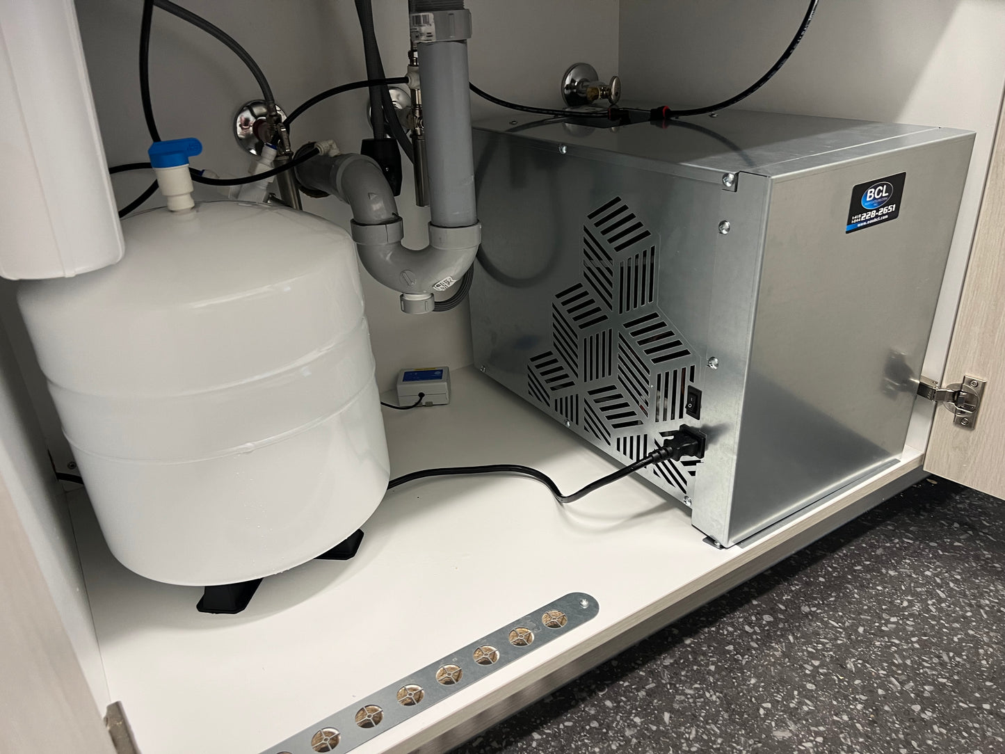 Installation d’un refroidisseur sous comptoir IceBoxx avec réservoir et plomberie raccordée.
